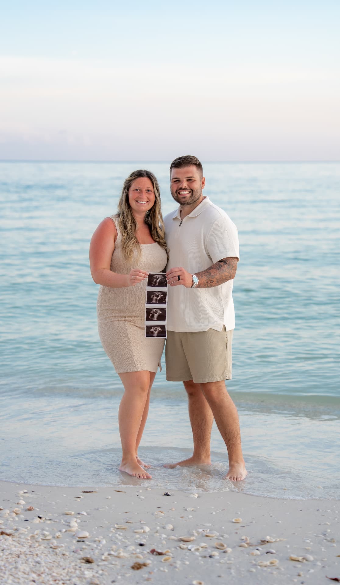 Expectant mother in a flowing dress photographed on a Florida beach at sunset